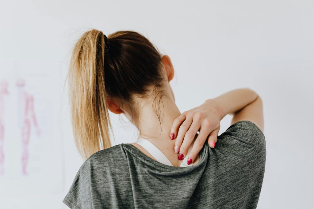 Mujer tocándose el cuello con gesto de molestia, símbolo de contracturas musculares en vacaciones