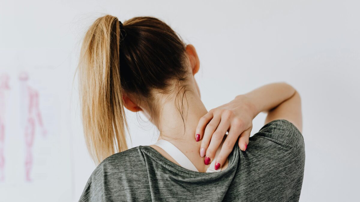 Mujer tocándose el cuello con gesto de molestia, símbolo de contracturas musculares en vacaciones