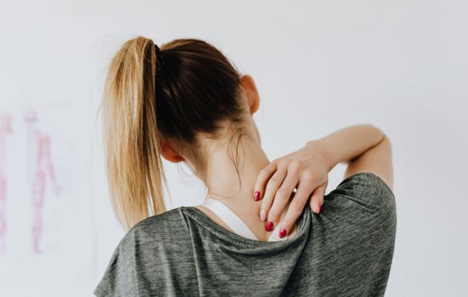 Mujer tocándose el cuello con gesto de molestia, símbolo de contracturas musculares en vacaciones