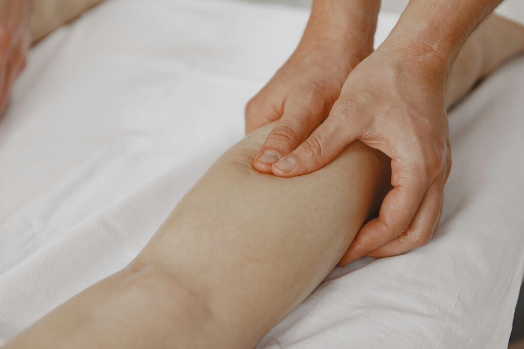 Masaje de drenaje linfático manual en la pierna para aliviar la retención de líquidos y piernas cansadas en verano.