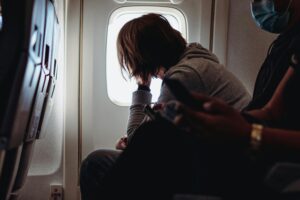 Chico sentado de forma incorrecta en un avión, causando dolor de espalda al viajar durante vuelos prolongados