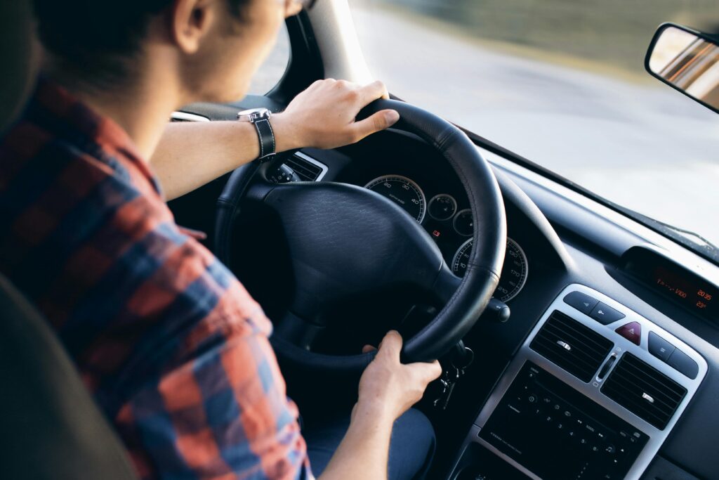 Hombre conduciendo un coche con postura ergonómica para evitar el dolor de espalda al viajar.