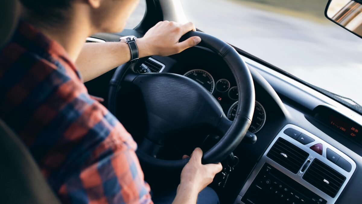 Hombre conduciendo un coche con postura ergonómica para evitar el dolor de espalda al viajar.