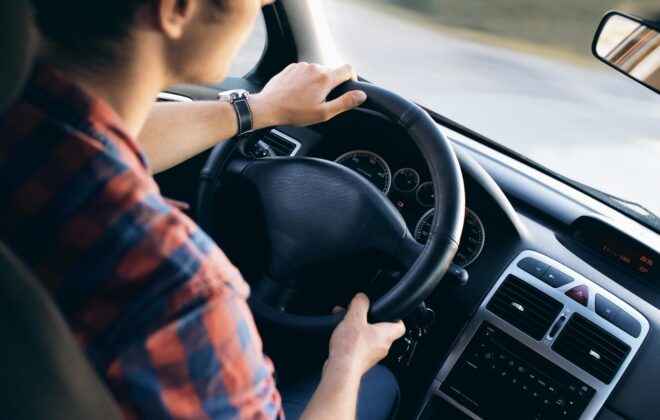 Hombre conduciendo un coche con postura ergonómica para evitar el dolor de espalda al viajar.