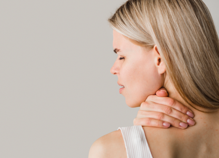Mujer tocándose el cuello con expresión de molestia, mostrando dolor cervical o tortícolis