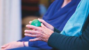Persona mayor realizando ejercicios con una pelota de manos en Las Águilas y Aluche, guiada por fisioterapeuta para mejorar fuerza y movilidad.