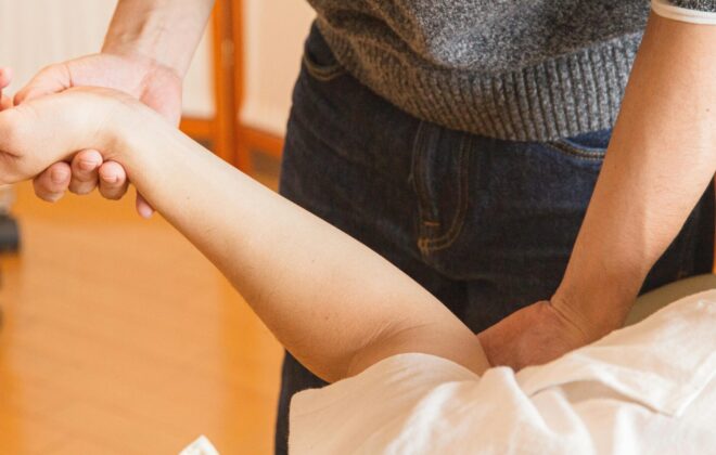 Fisioterapeuta trata el brazo de un paciente con osteoporosis en Centro Fisher, clínica de fisioterapia en Las Águilas - Aluche, Madrid.