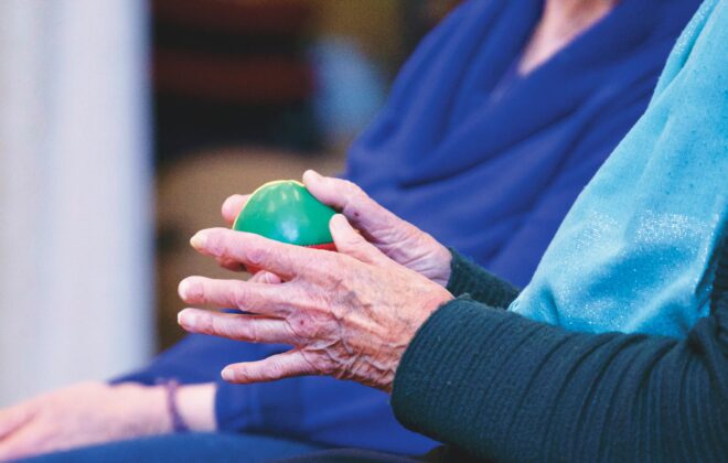 Manos de un paciente realizando ejercicios de fisioterapia post-ictus con una pelota para mejorar fuerza y coordinación.