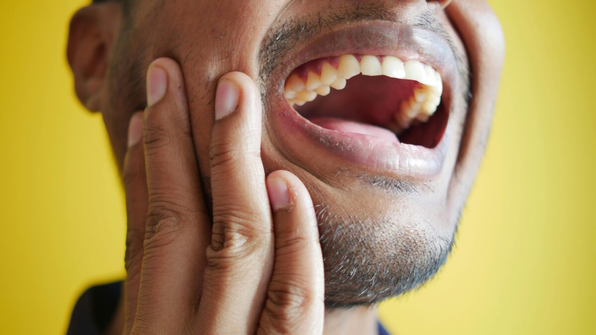 Dolor mandibular y cervical por disfunción de la ATM y bruxismo, paciente tocándose la mandíbula.