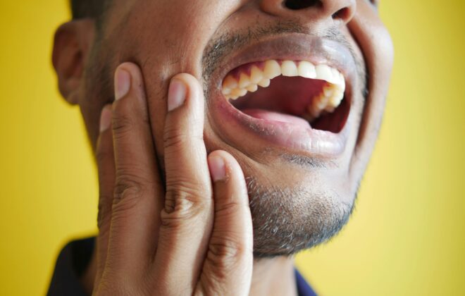 Dolor mandibular y cervical por disfunción de la ATM y bruxismo, paciente tocándose la mandíbula.