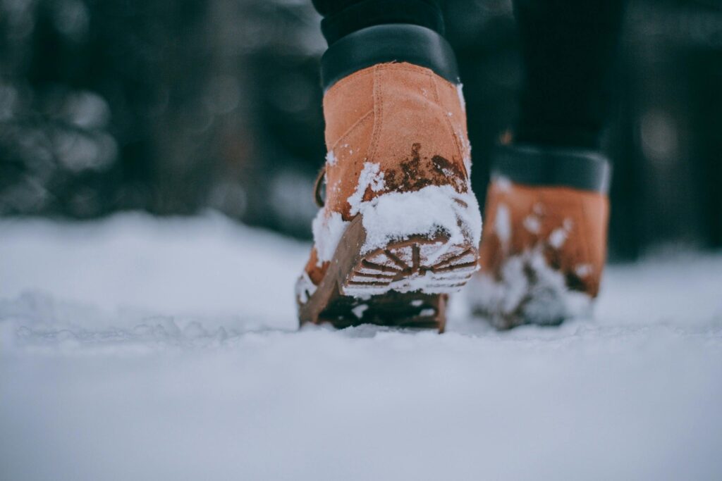 Problemas derivados de una mala pisada: persona con botas caminando por la nieve mostrando cuidado de pies y postura