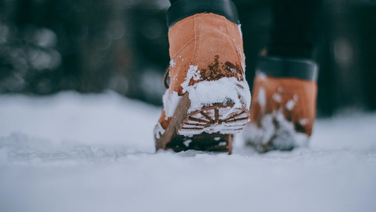 Problemas derivados de una mala pisada: persona con botas caminando por la nieve mostrando cuidado de pies y postura