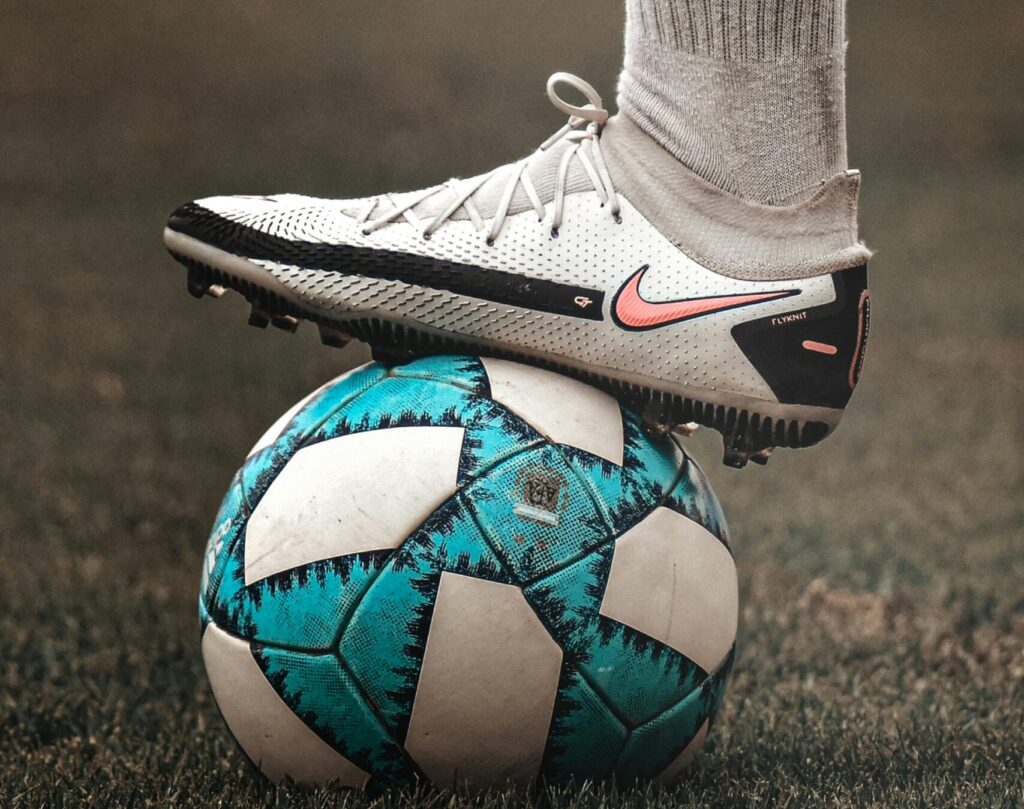 Pie con bota de fútbol sobre balón, ilustrando lesiones comunes en pies de futbolista