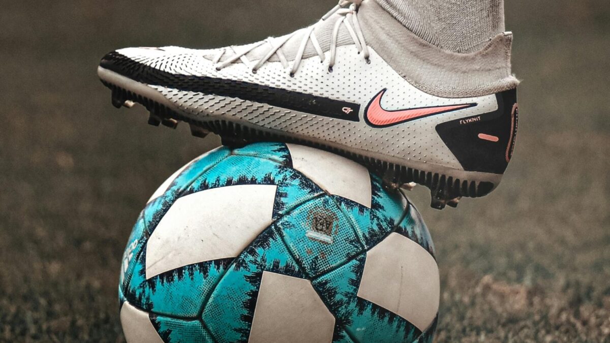 Pie con bota de fútbol sobre balón, ilustrando lesiones comunes en pies de futbolista
